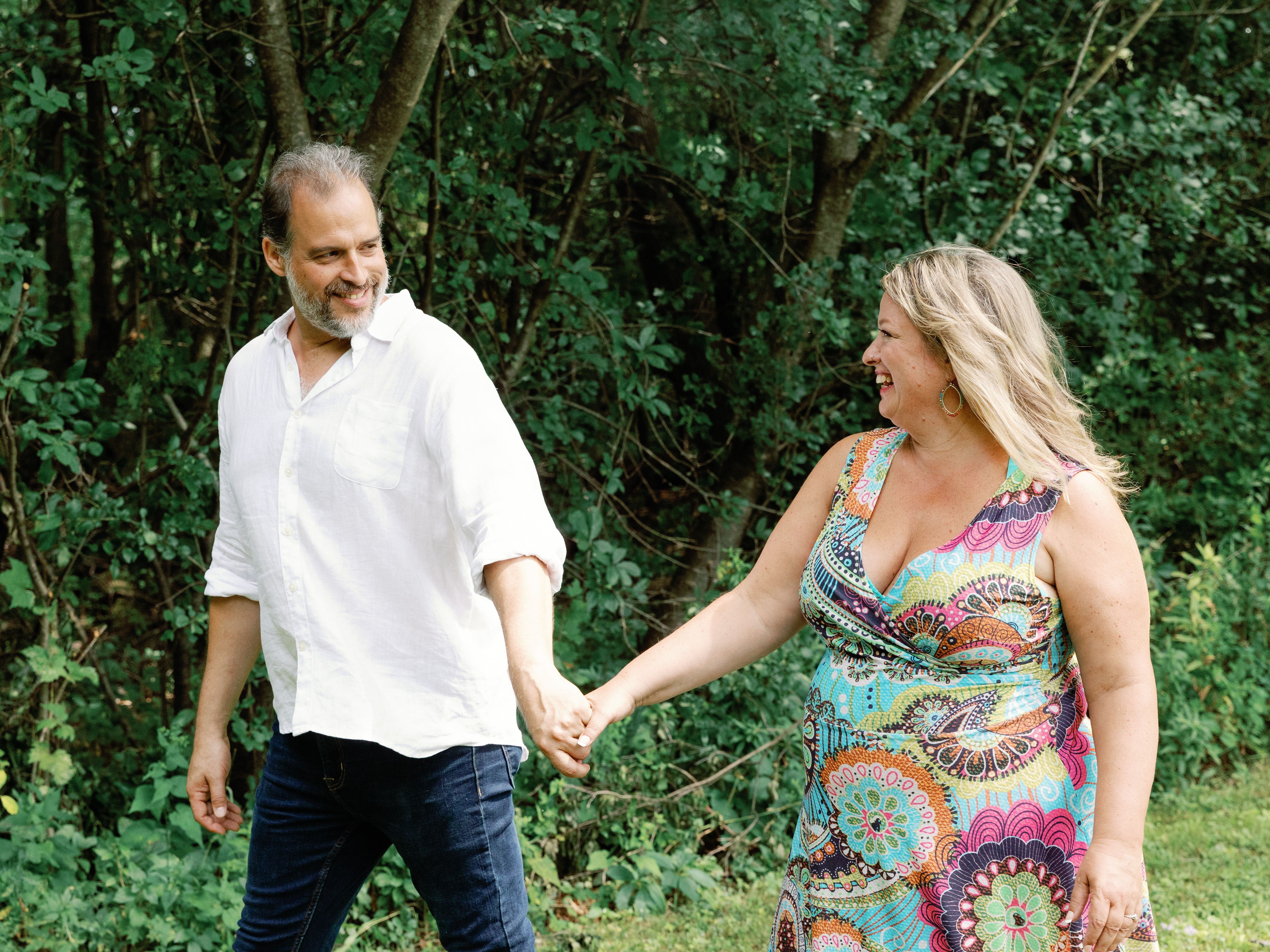 Dr. Christine Lebiecki laughing outdoors, walking hand in hand through the trees